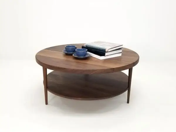 A walnut coffee table with three tapered legs and a tea set on top of it.