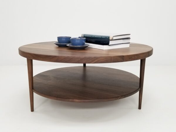 A walnut coffee table with three tapered legs and a tea set on top of it.