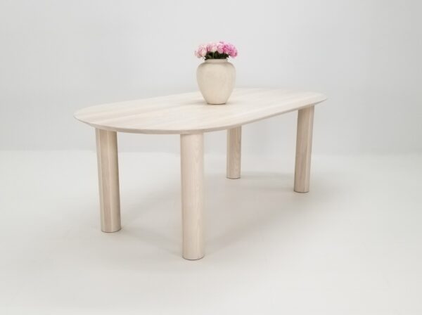 Our COVE dining table in sunwashed ash, with a vase on top of it.