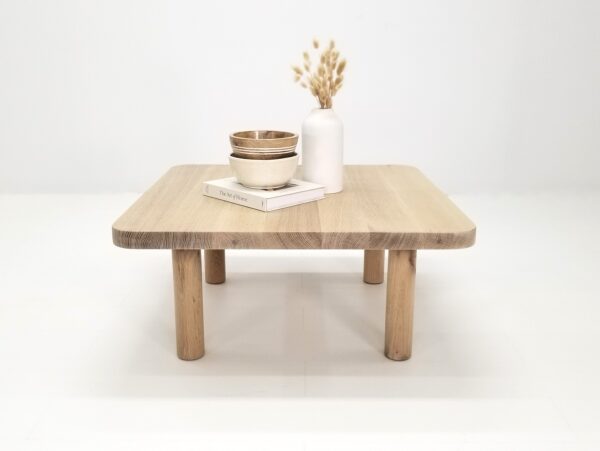 A seawashed, quarter-sawn white oak coffee table with vases and a book on top.