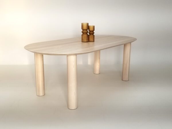Our oval top COVE dining table in sunwashed ash, with vases on top of it.