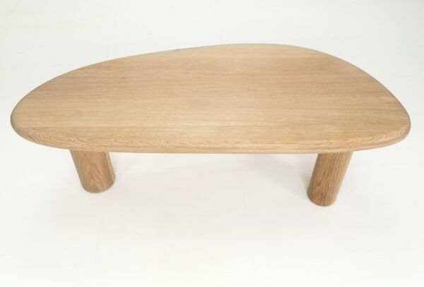 A close up of the top of a freeform coffee table in natural white oak.