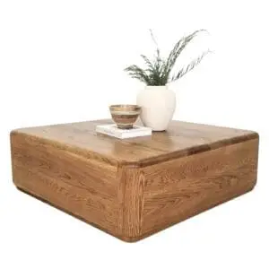 A square coffee table with a vase on top of it.