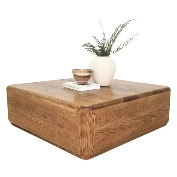 A square coffee table with a vase on top of it.