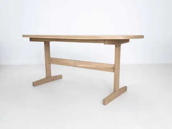 A oval top trestle dining table with two legs.