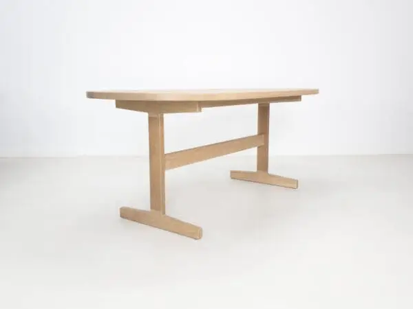 A oval top trestle dining table with two legs.