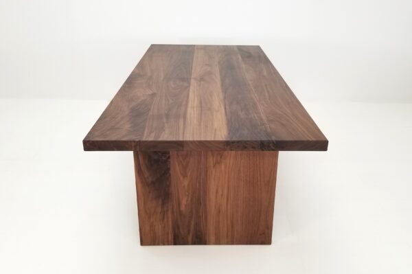 A close up of a 2" thick walnut dining table.