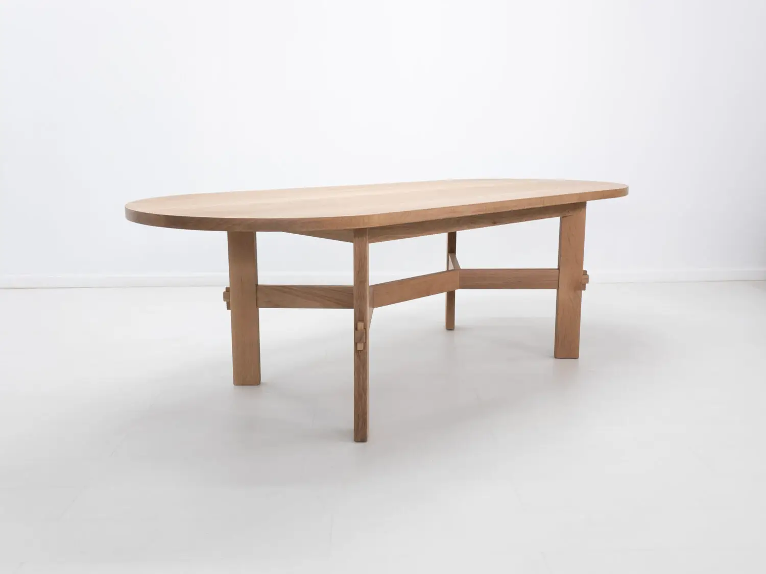 COLT dining table crafted from solid white oak with an oval top and angular stretcher base