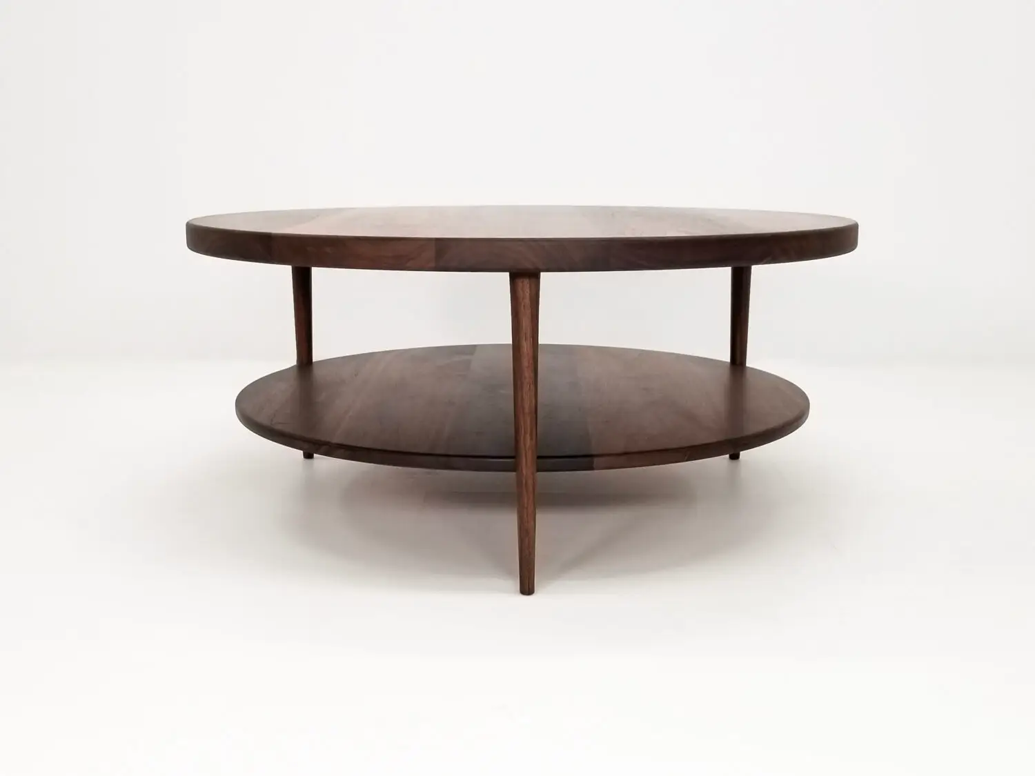 Handcrafted walnut coffee table featuring a 1⅜ inch thick round top with a smooth finish