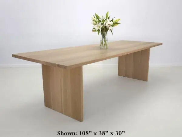 A white oak panel dining table with flowers on top of it.