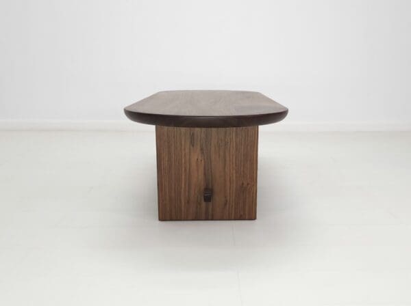 A solid walnut trestle coffee table.