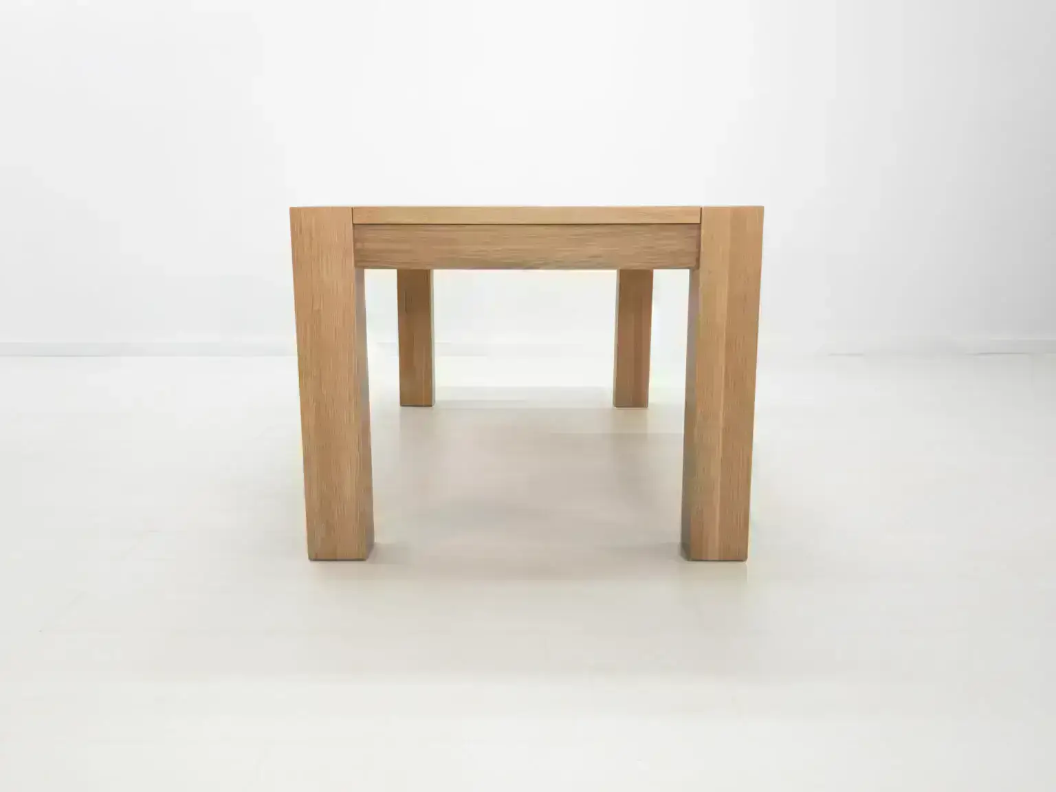 JAQI dining table in seawashed white oak finish featuring a seamless top with breadboard ends