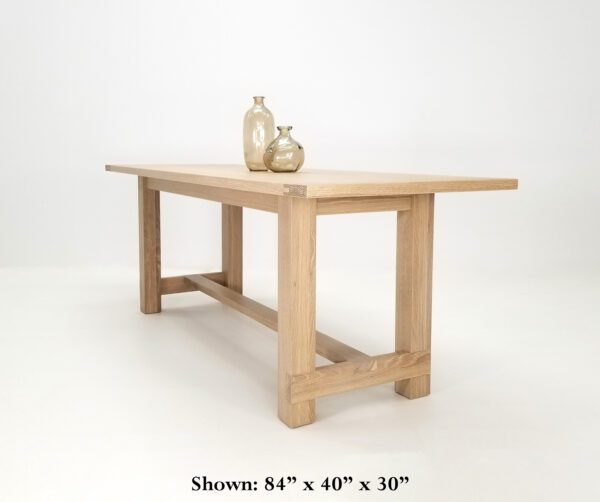 A trestle base dining table with vases on top of it.