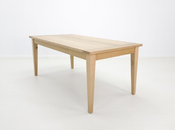 A white oak dining table with tapered legs.