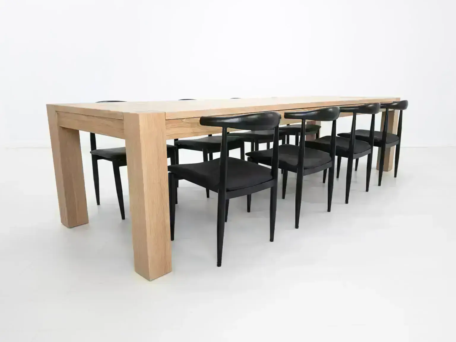 JAQI dining table in seawashed white oak finish featuring a seamless top with breadboard ends