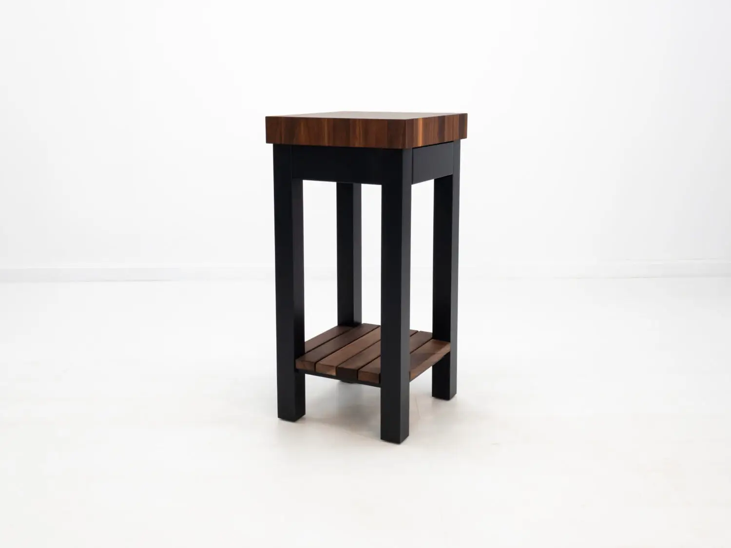 Three quarter view of LUCA island in walnut and black showing end grain butcher block top and slatted shelf