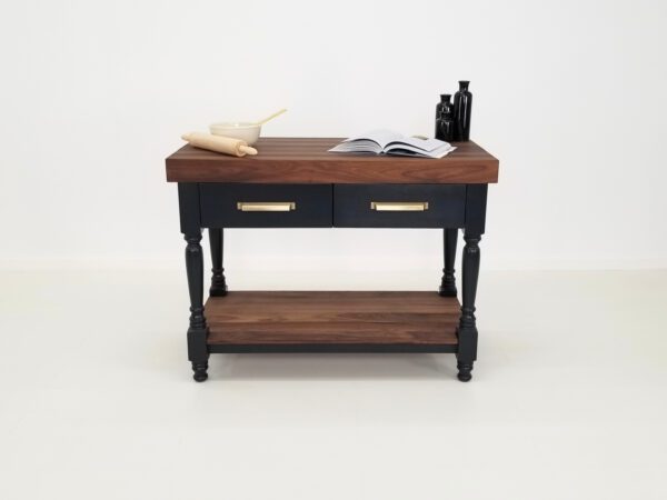 A walnut butcher block kitchen island with various chef utensils on top of it.