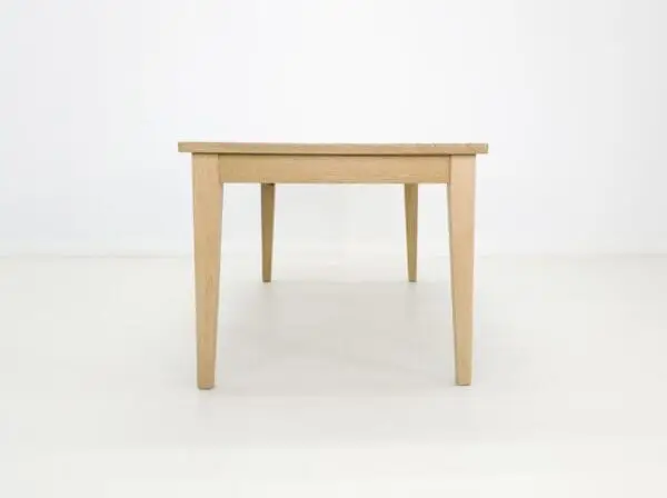 A white oak dining table with tapered legs.