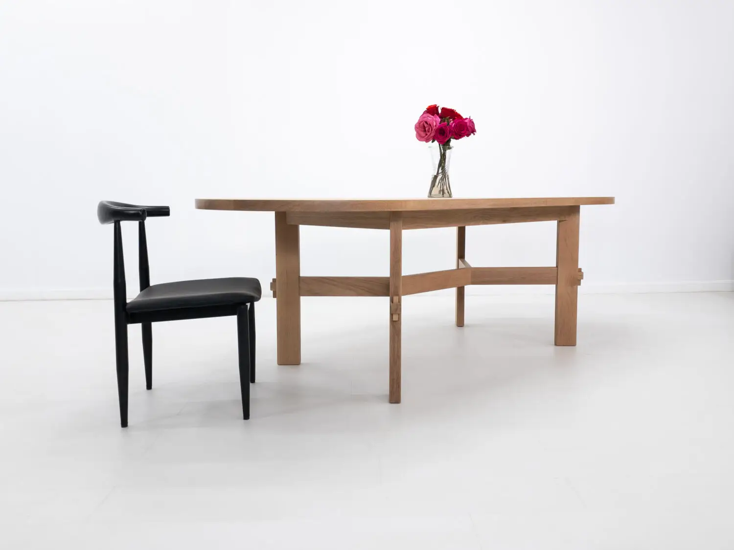 Custom COLT dining table with solid rectangular legs and a striking angular stretcher design