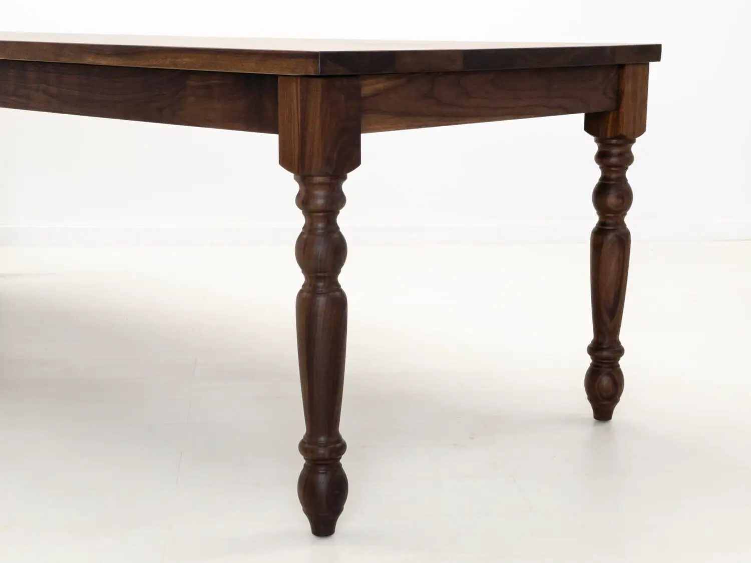 Close up of the TESS tables 1⅜ inch thick plank top highlighting the natural walnut grain and smooth hardwax oil finish