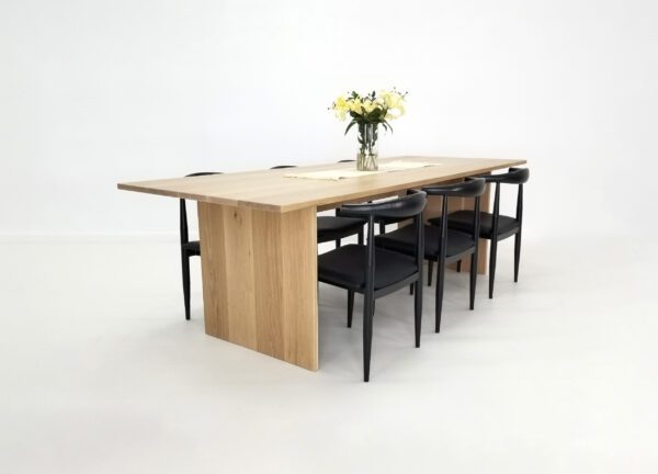 A white oak panel table with chairs around it.