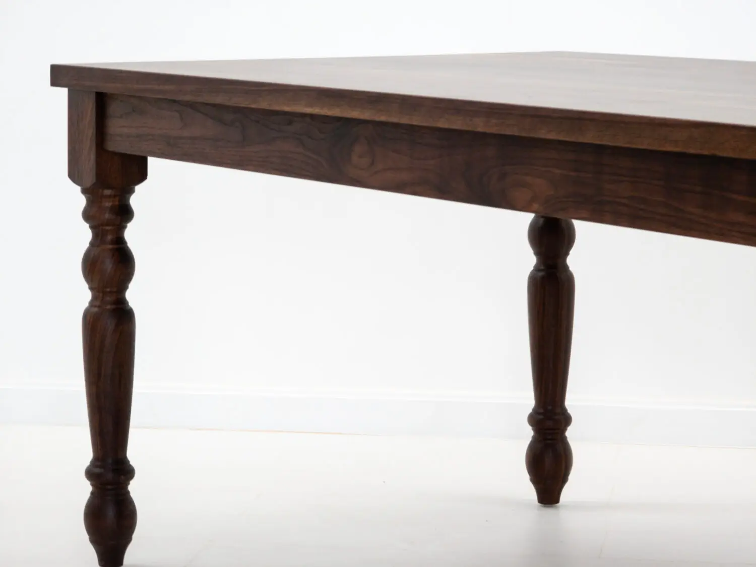 Close up of the TESS tables 1⅜ inch thick plank top highlighting the natural walnut grain and smooth hardwax oil finish