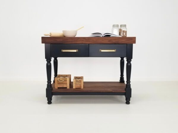 A walnut butcher block kitchen island with various chef utensils on top of it.