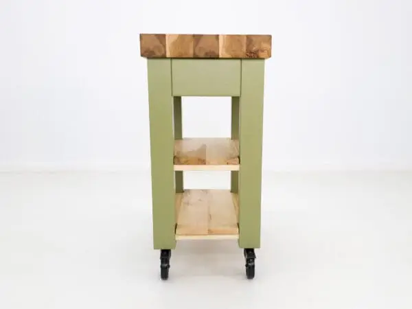 Green kitchen island with wood top and shelves.