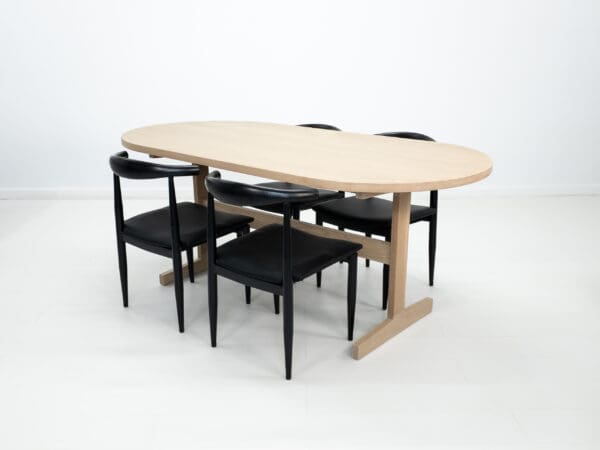 A oval top trestle dining table with chairs around it.