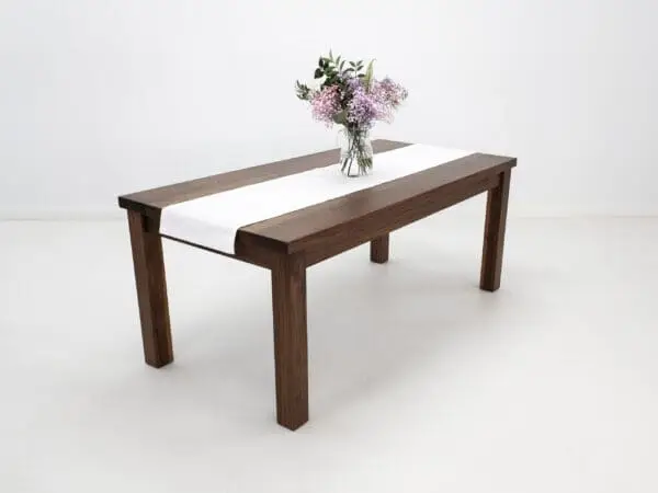 A walnut dining table with decor on top of it.