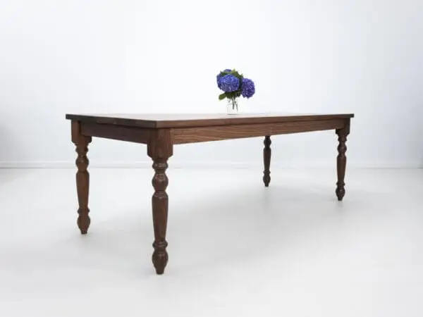 A turned leg dining table with flowers on top of it.