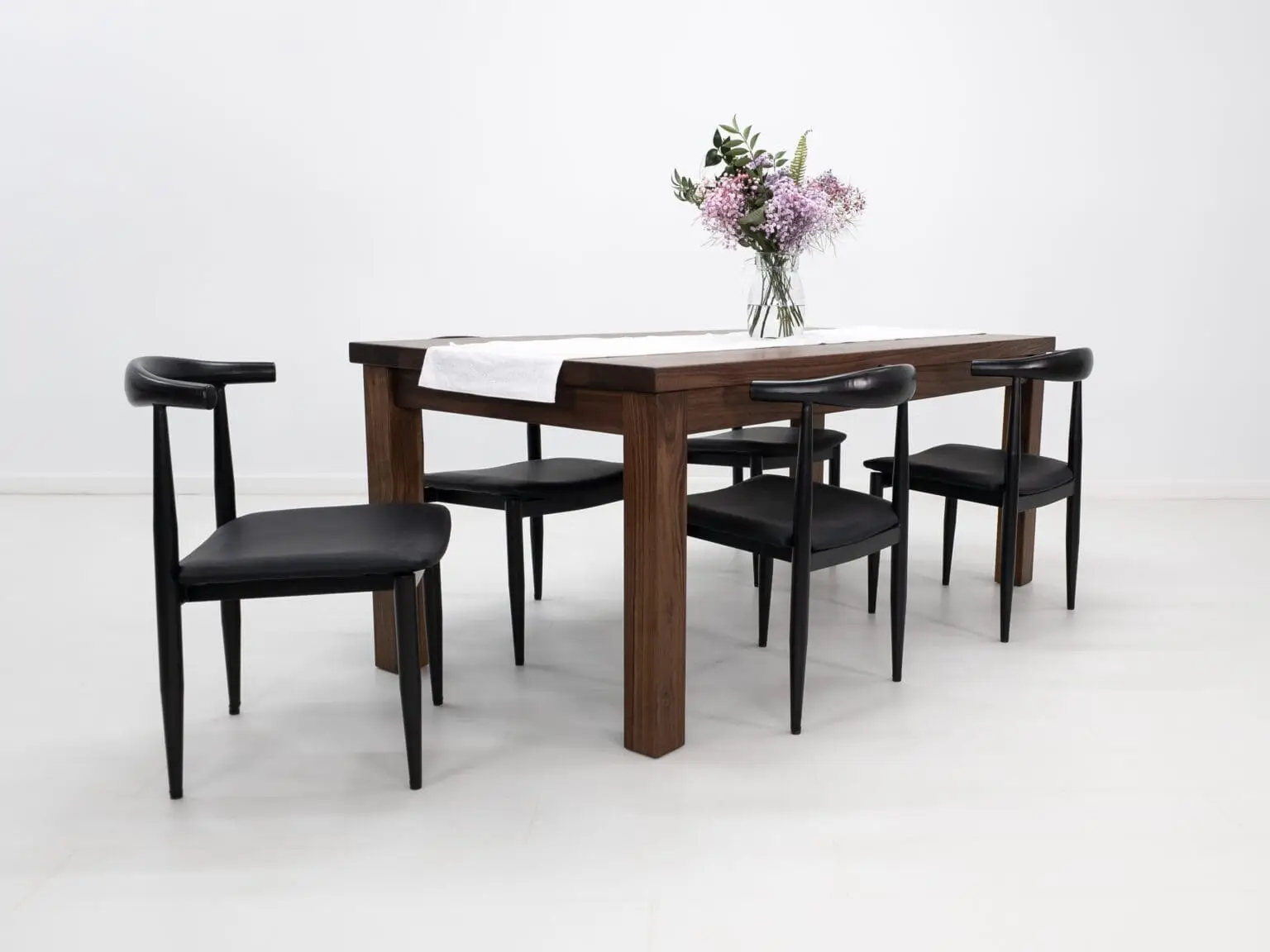 A walnut dining table with decor on top of it and chairs seated around the table