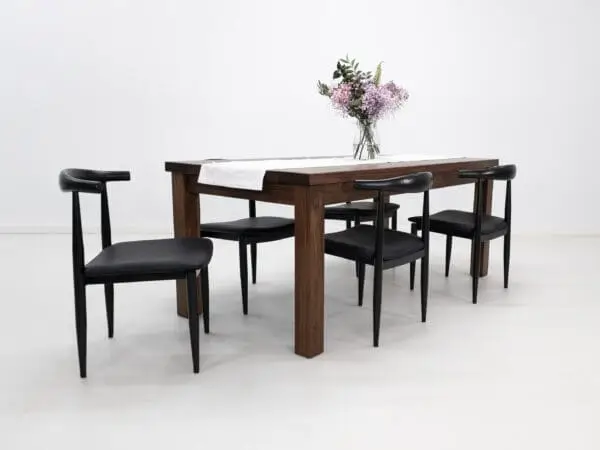 A walnut dining table with decor on top of it and chairs seated around the table.