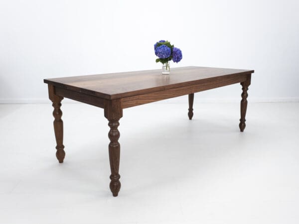 A turned leg dining table with flowers on top of it.