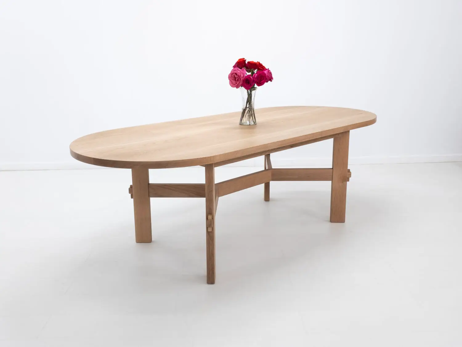 Custom COLT dining table with solid rectangular legs and a striking angular stretcher design