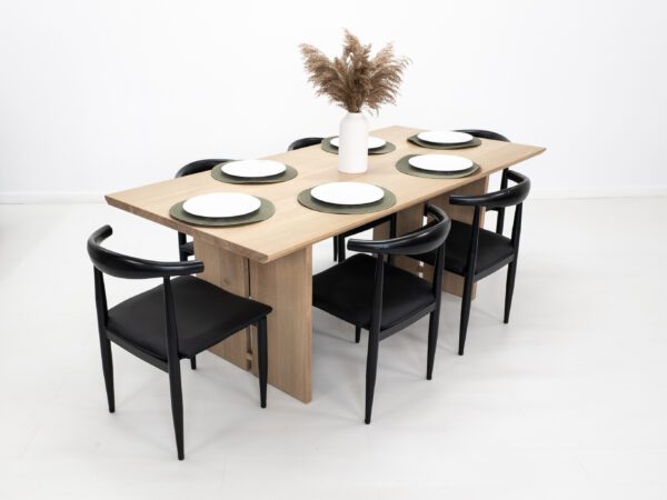 A split leg dining table with tableware on top of it.