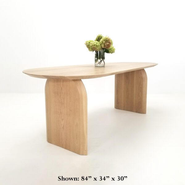 A curved dining table with curved legs and flowers on top of it.