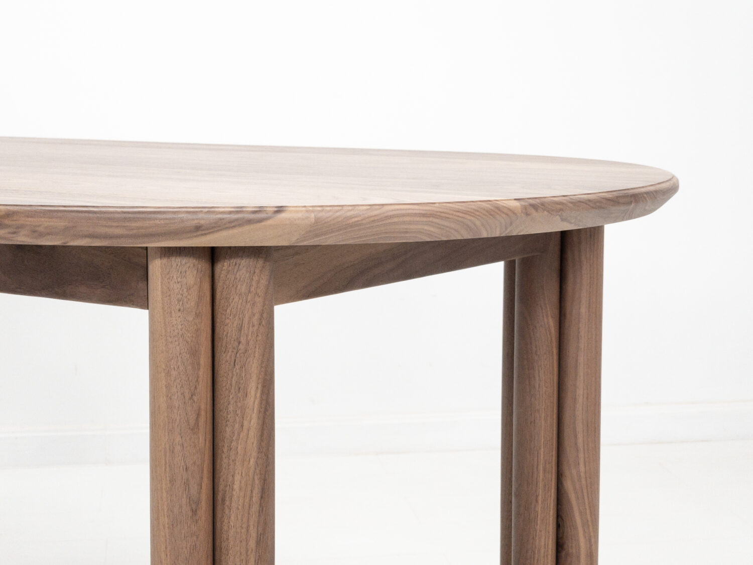Handmade walnut dining table with soft sculpted edges and rounded legs