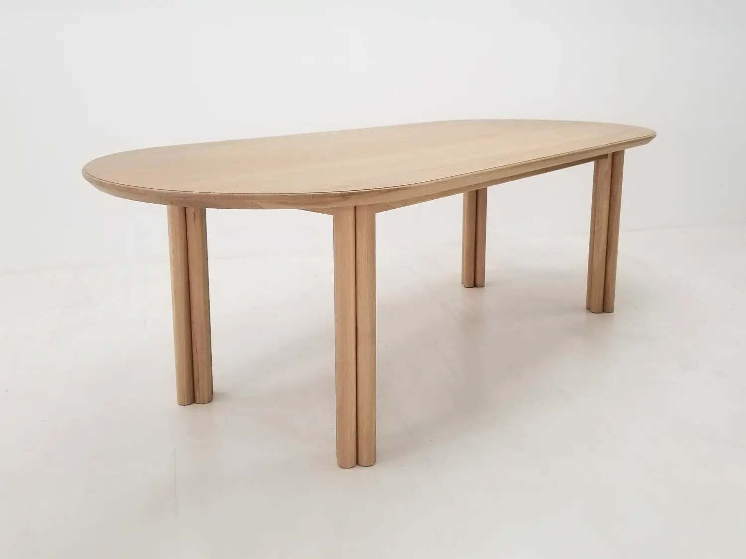 BEAU dining table in natural white oak with a 1⅜ inch thick oval top and clustered cylinder legs