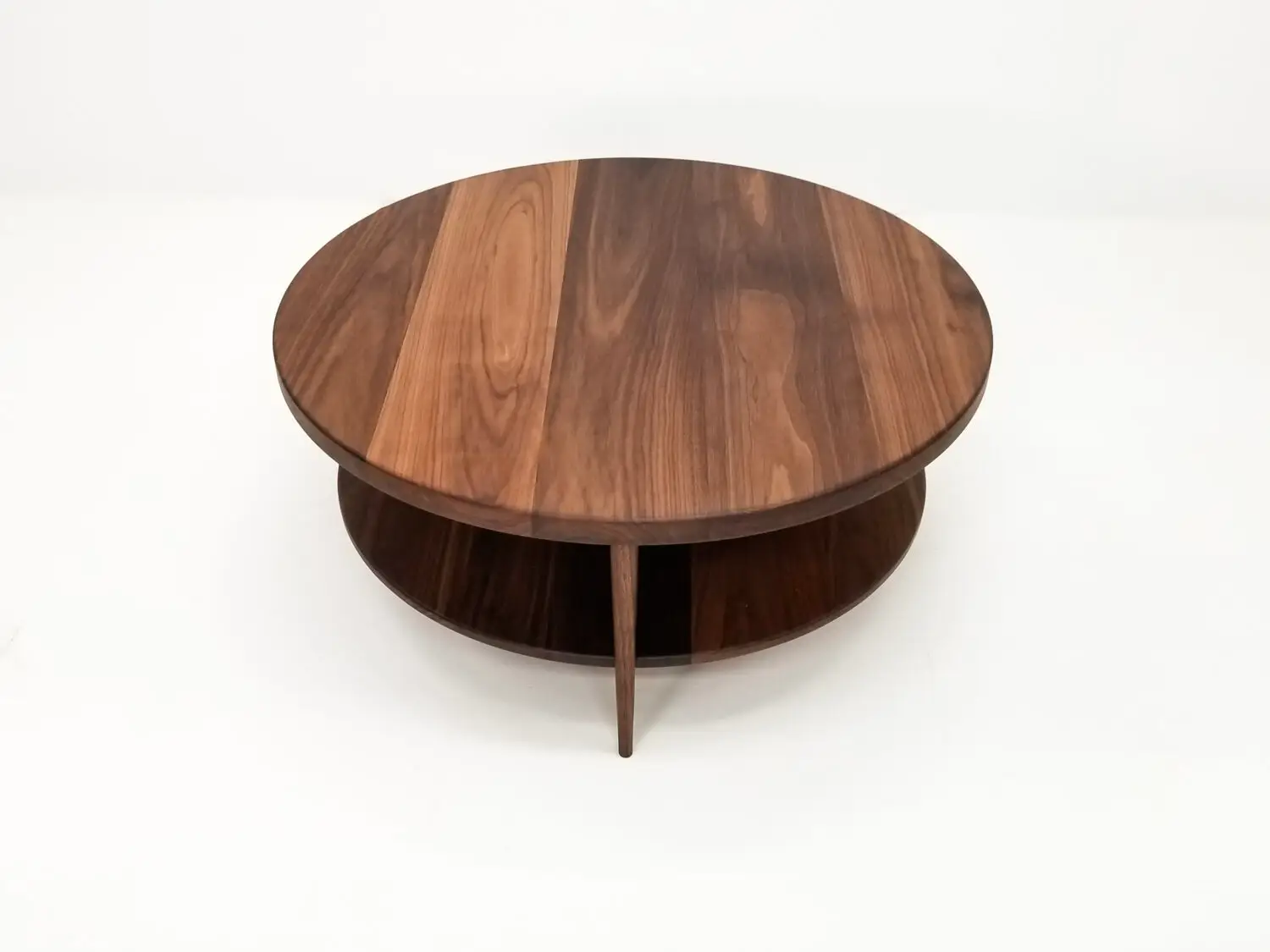 Handcrafted walnut coffee table featuring a 1⅜ inch thick round top with a smooth finish
