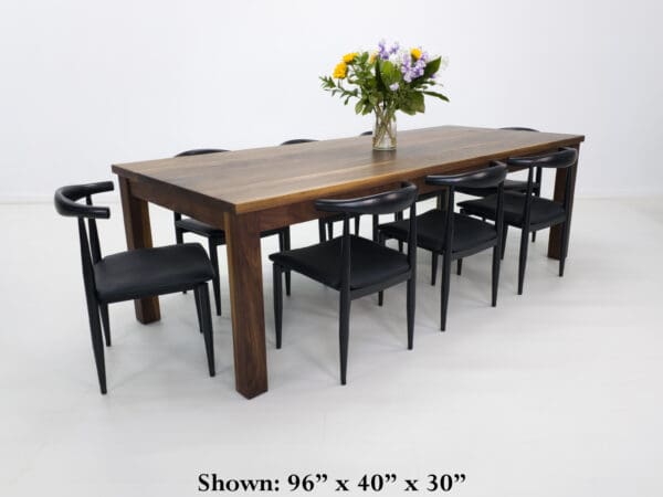A walnut dining table with decor on top of it and chairs seated around the table.