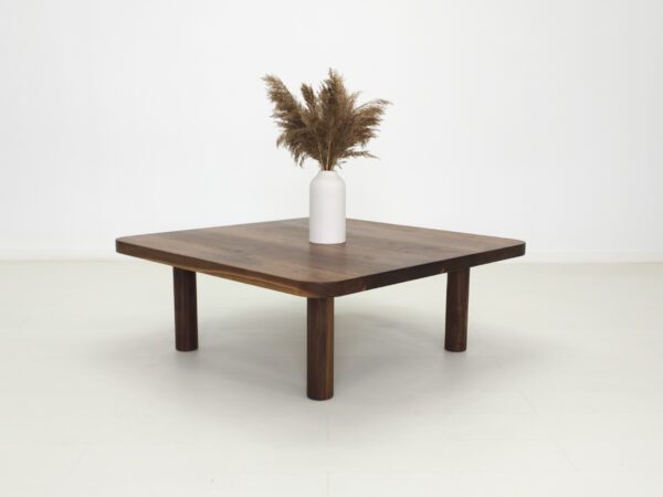 A walnut coffee table with four legs and a vase on top of it.