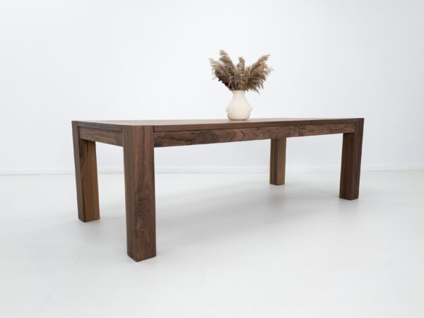 A solid walnut dining table with decor on top of it.