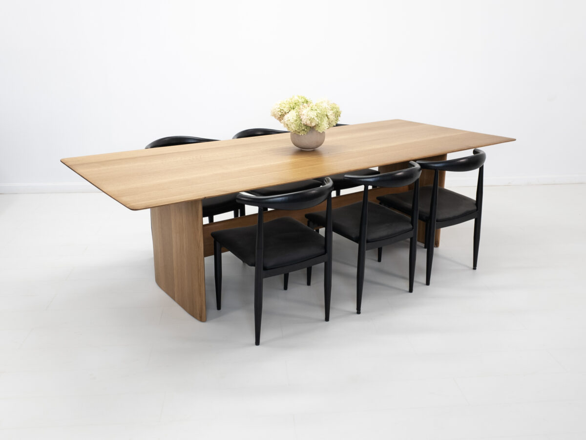 Side view of the THEO dining table with a trestle base and softly rounded corners