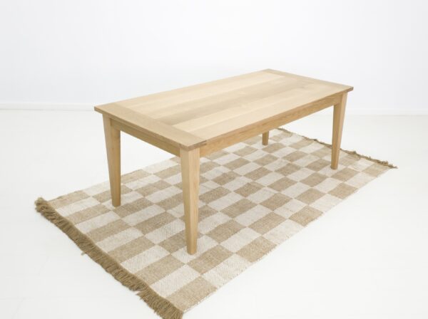 A white oak dining table on a rug.