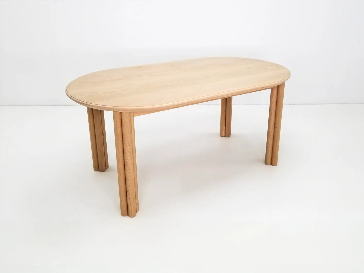 BEAU dining table in natural white oak with a 1⅜ inch thick oval top and clustered cylinder legs