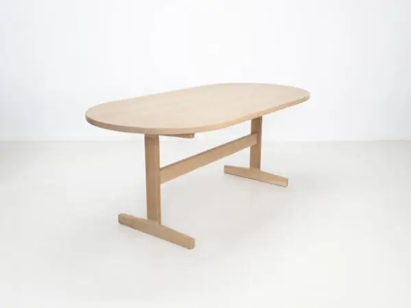 A oval top trestle dining table with two legs.