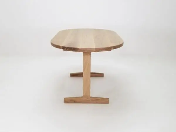 A oval top trestle dining table with two legs.