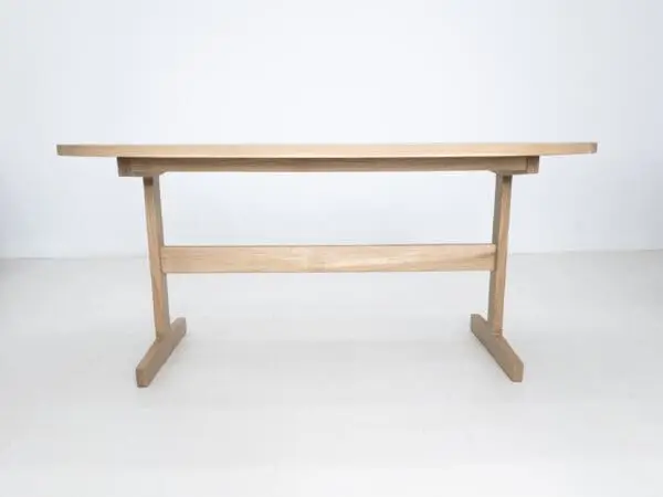 A oval top trestle dining table with two legs.