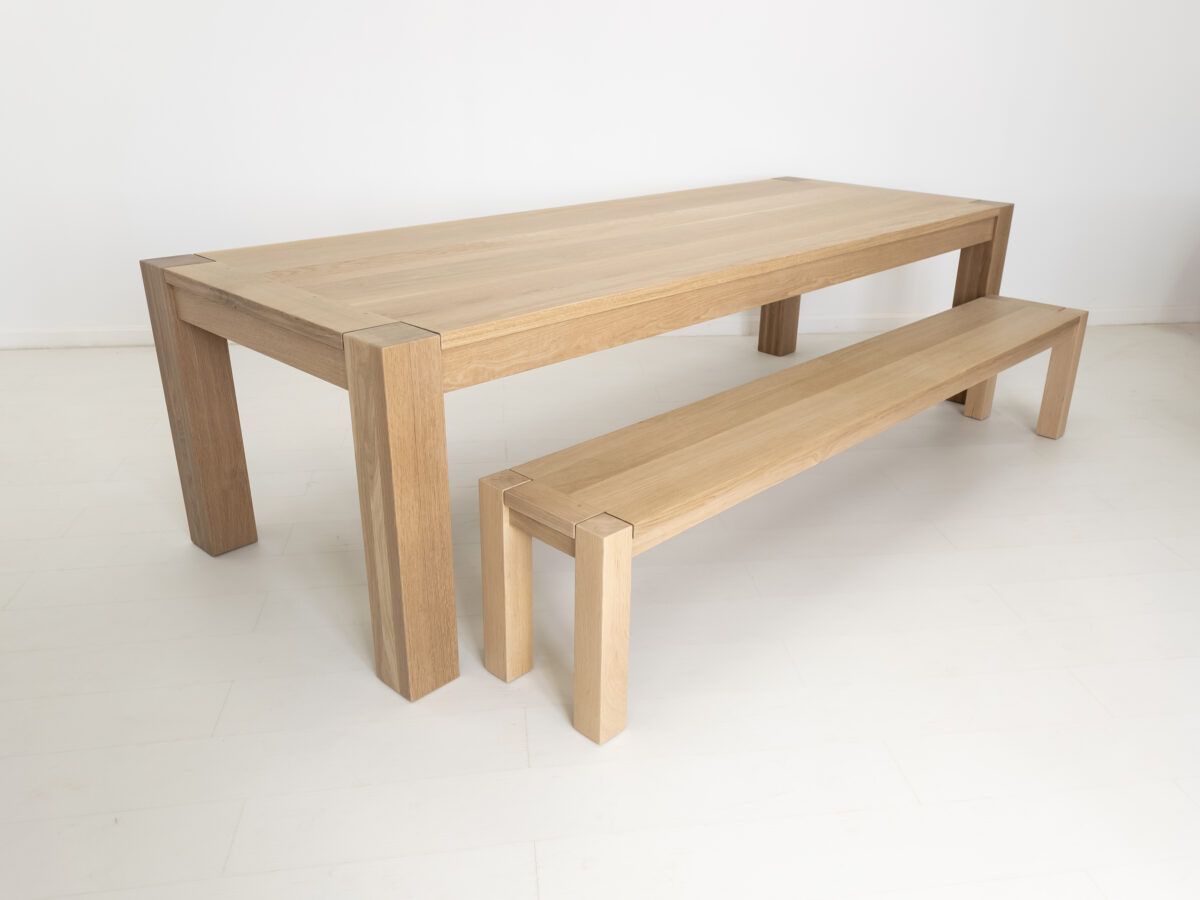 Close up of the JAQI dining table in natural white oak highlighting the 5 inch square legs and matching bench